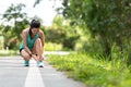 Runner young asia woman tying laces of running shoes before jogging through the road in the workout nature park. Royalty Free Stock Photo