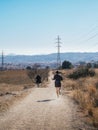 Runners on a Dusty Trail with City and Hills in the Background Royalty Free Stock Photo