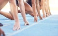 Runners with hands on start line on the track for a race, ready to run. Racing challenge or sprint at sports event with Royalty Free Stock Photo