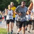 Runners racing a 5K around Belmont Lake giving the peace sign