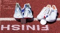 Runniners racing spikes at finish line with gold and siver medals