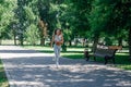 running attractive young sporty woman warming up, stretching in grey sportswear in park in sunny summer day Royalty Free Stock Photo