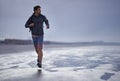 Running, beach and man with vacation, travel and exercise with nature, explore and ocean. Person, runner and guy with Royalty Free Stock Photo