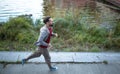 Running beardy male on river bank in the city.