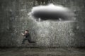 Running businessman holding tablet with dark clouds raining and