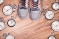 Running equipment. Stopwatch and running women shoes. Time for run. Sport running accessories on the wooden floor.