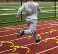 Running running fast over small yellow hurdles on a track