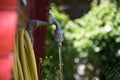 Running faucet with yellow garden hose next to red garden shed Royalty Free Stock Photo