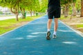 Running feet male in runner jogging exercise with old shoes for health lose weight concept on track rubber cover blue public park Royalty Free Stock Photo