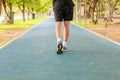 Running feet male in runner jogging exercise with old shoes for health lose weight concept on track rubber cover blue public park Royalty Free Stock Photo