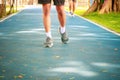 Running feet male in runner jogging exercise with old shoes for health lose weight concept on track rubber cover blue public park Royalty Free Stock Photo