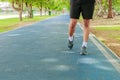 Running feet male in runner jogging exercise with old shoes for health lose weight concept on track rubber cover blue public park Royalty Free Stock Photo