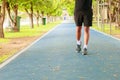 Running feet male in runner jogging exercise with old shoes for health lose weight concept on track rubber cover blue public park Royalty Free Stock Photo