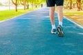 Running feet male in runner jogging exercise with old shoes for health lose weight concept on track rubber cover blue public park