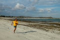 Running man jogging on beach. Indonesian teenager in shorts and a yellow T-shirt running along the beach. Young athlete trains by Royalty Free Stock Photo