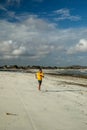 Running man jogging on beach. Indonesian teenager in shorts and a yellow T-shirt running along the beach. Young athlete trains by Royalty Free Stock Photo