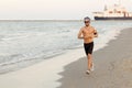 Running guy jogging on beach, training outside working out. Fit young male sport fitness model exercising in full body Royalty Free Stock Photo