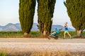 Running mother with stroller enjoying motherhood at sunset lands