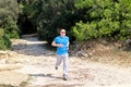 Running muscular man athlete runner training outdoor in forest. Running runner sportsmen wearing sportswear in cross country. Royalty Free Stock Photo