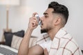 A sick man spraying nasal drops to his nose