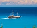 Running pirate corsair style boat ship in amazing Greece island bay with swimming people, beach in Ionian Sea blue water, Famous G