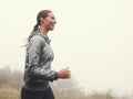 Running puts a smile on her face. A young woman jogging on a country road on a misty morning. Royalty Free Stock Photo