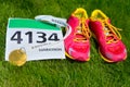 Running shoes, marathon race bib (number) and finisher medal on grass background, Royalty Free Stock Photo