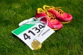 Running shoes, marathon race bib (number) and finisher medal on grass background, Royalty Free Stock Photo