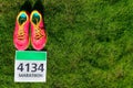 Running shoes and marathon race bib (number) on grass background, sport, fitness and healthy lifestyle