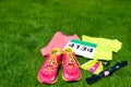 Running shoes, marathon race bib number, runner gear and energy gels on grass background, sport competition, fitness