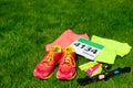 Running shoes, marathon race bib number, runners gear and energy gels on grass background, sport, fitness and healthy lifestyle