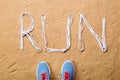 Running shoes and run sign made of shoelaces, sand Royalty Free Stock Photo