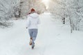 Running sport woman. Female runner jogging in cold winter forest wearing warm sporty running clothing and gloves Royalty Free Stock Photo