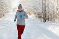 Running sport woman. Female runner jogging in cold winter forest wearing warm sporty running clothing and gloves Royalty Free Stock Photo