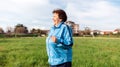 Running and sports activity. An elderly smiling woman in sports clothes runs through a green field. Side view. The