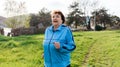 Running and sports activity. Portrait of mature happy woman in sports clothes running at the park. Concept of the International