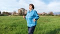 Running and sports activity. Portrait of mature smiling grandmother in sports clothes runs through a green field. The