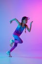 Running technique. Sportive girl, junior runner in stylish sportswear and cap posing isolated on gradient pink-blue Royalty Free Stock Photo