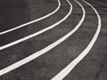 Running track closeup with white curving lines painted on black Royalty Free Stock Photo