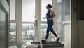 Running on treadmill. Fitness cardio workout at home. Young motivated woman is hard training on treadmill at home in balcony, tryi