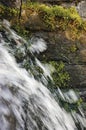 Running water cascade waterfall streaming splashes, decorative granite stonewall background, green moss, grey rock stone wall Royalty Free Stock Photo