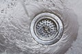 Running water flowing going down drain in stainless steel kitchen sink Royalty Free Stock Photo