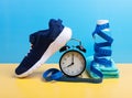 Running, weight loss concept with sneakers, bottle of water, towel, timer and measuring tape set over blue wall background