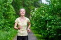 Running woman atletic spotsman trains in the summer park. Outdoor fitness portrait after rain