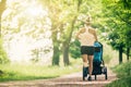 Running woman with baby stroller enjoying summer in park Royalty Free Stock Photo