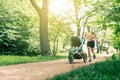 Running woman with baby stroller enjoying summer in park Royalty Free Stock Photo