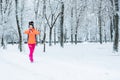 Running woman looking at smartwatch, checking heartrate and pulse during jogging in winter park. Fitness woman setting