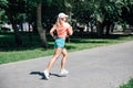 running young sporty woman in park in sportswear on background of green trees on grey tiles in sunny windy summer day Royalty Free Stock Photo