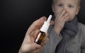 A runny nose is treated with a medicine from a nasal spray. Nasal drops on a black background. Concept for treating a baby cold or