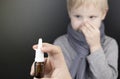 A runny nose is treated with a medicine from a nasal spray. Nasal drops on a black background. Concept for treating a baby cold or